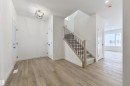 Entry foyer featuring wood-finish flooring, a modern geometric flush-mount light fixture, a staircase with light wood newel posts and black metal spindles, and white paneled doors - 162 Caldeon Crescent, Spruce Grove, AB  - Indoor Photo Showing Other Room 