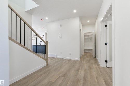 Contemporary interior featuring light wood-finish flooring and a staircase with a light wood handrail and black metal balusters - 162 Caldeon Crescent, Spruce Grove, AB - Indoor Photo Showing Other Room