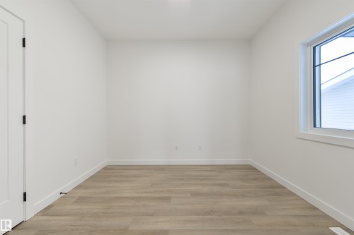 Bright interior space featuring a window with white trim, wood-finish flooring, white walls, and a white door with black hardware - 162 Caldeon Crescent, Spruce Grove, AB - Indoor Photo Showing Other Room