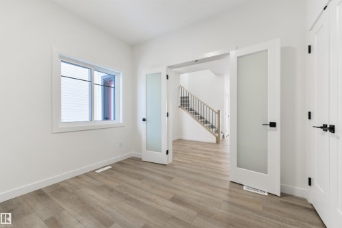Versatile interior space featuring wood-finish flooring, white baseboards, and a large window with white trim - 162 Caldeon Crescent, Spruce Grove, AB - Indoor Photo Showing Other Room