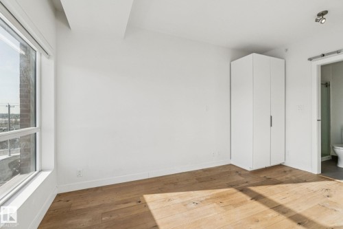 This room features hardwood floors, a large window, a built-in wardrobe, and white walls - #321 63 Inglewood Park, Calgary, AB - Indoor Photo Showing Other Room