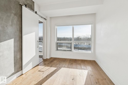 This bright room features wide plank wood flooring and a large window providing ample natural light - #321 63 Inglewood Park, Calgary, AB - Indoor Photo Showing Other Room