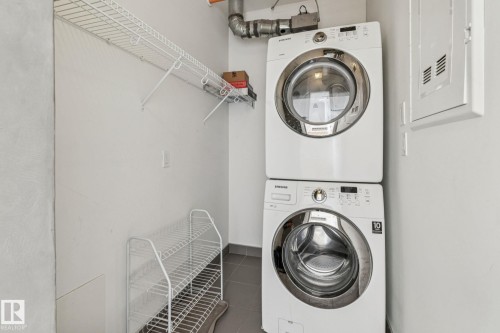 Dedicated laundry area with a stacked washer and dryer, complete with overhead wire shelving for storage - #321 63 Inglewood Park, Calgary, AB - Indoor Photo Showing Laundry Room