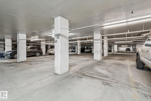 Convenient underground parking area featuring concrete floors and ceiling, illuminated by overhead fluorescent lighting - #321 63 Inglewood Park, Calgary, AB - Indoor Photo Showing Garage