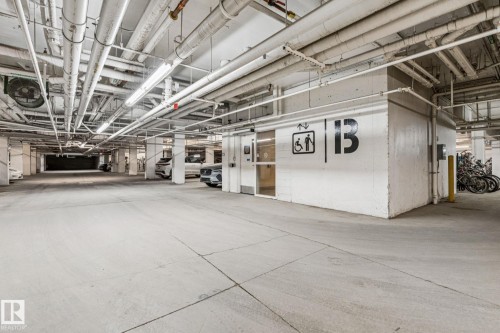 The property includes a parking garage with concrete flooring, exposed overhead piping, and fluorescent lighting - #321 63 Inglewood Park, Calgary, AB - Indoor Photo Showing Garage