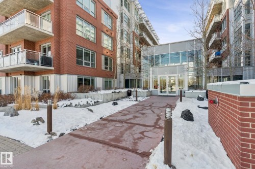 The property features a brick exterior with balconies, large windows, and a glass-enclosed entrance - #321 63 Inglewood Park, Calgary, AB - Outdoor