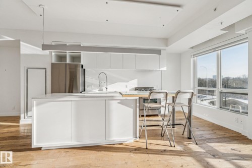 The kitchen features a large island with white cabinetry, stainless steel appliances, and a gas range - #321 63 Inglewood Park, Calgary, AB - Indoor