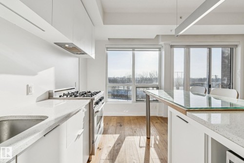 Modern kitchen with white cabinetry, light-colored countertops, a stainless steel range, and hardwood floors - #321 63 Inglewood Park, Calgary, AB - Indoor Photo Showing Kitchen