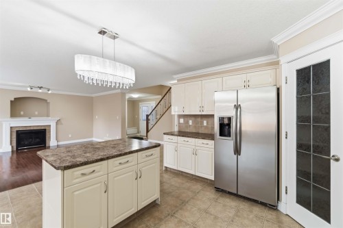 Kitchen featuring an island with storage, granite-look countertops, stainless steel refrigerator, and tiled flooring - 16412 60 Street, Edmonton, AB - Indoor Photo Showing Kitchen