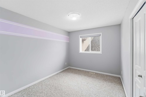 Carpeted room featuring a single window with roller shade, overhead flush mount light fixture, textured ceiling, and white baseboards - 16412 60 Street, Edmonton, AB - Indoor Photo Showing Other Room