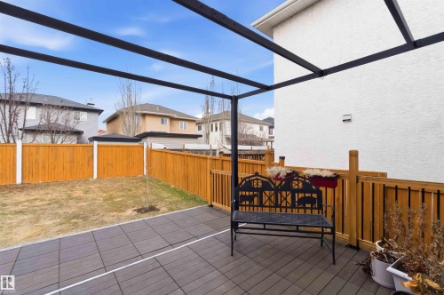 Patio featuring a black metal pergola structure, dark composite decking, and a wood fence enclosing a grass lawn - 16412 60 Street, Edmonton, AB - Outdoor With Deck Patio Veranda