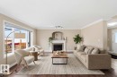 Spacious living area featuring wood-finish flooring, a white trim package, and a decorative fireplace with a mantel - 16412 60 Street, Edmonton, AB  - Indoor Photo Showing Living Room With Fireplace 