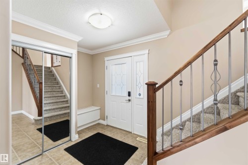 Entry foyer featuring tile flooring, a staircase with wood-finish handrail and metal balusters, and crown molding - 16412 60 Street, Edmonton, AB - Indoor Photo Showing Other Room