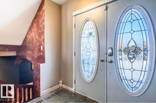 Double entry doors with decorative oval glass inserts, slate tile flooring, and a unique textured wall finish - 18633 122 Avenue, Edmonton, AB - Indoor Photo Showing Other Room
