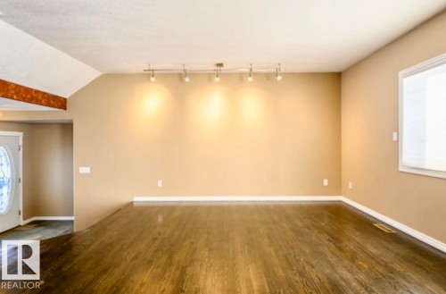 Spacious interior with dark wood-finish flooring, neutral wall paint, and a vaulted ceiling - 18633 122 Avenue, Edmonton, AB - Indoor Photo Showing Other Room