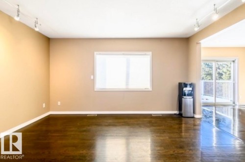 Spacious interior room featuring dark wood-finish flooring, a large window, and track lighting - 18633 122 Avenue, Edmonton, AB - Indoor Photo Showing Other Room