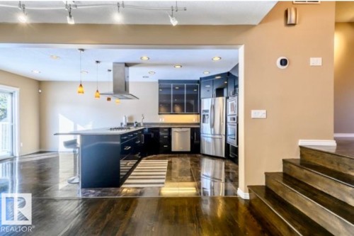 Kitchen featuring dark cabinetry, stainless steel appliances, a large island with seating, and pendant lighting - 18633 122 Avenue, Edmonton, AB - Indoor Photo Showing Kitchen