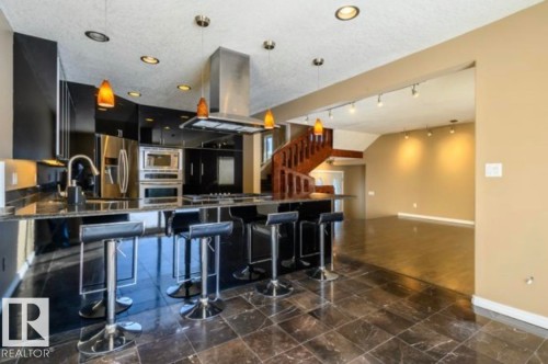 Gourmet kitchen featuring black cabinetry, stainless steel appliances, and a central island with bar seating - 18633 122 Avenue, Edmonton, AB - Indoor