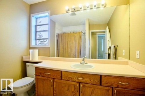 Bathroom featuring a wood-finish vanity with an integrated sink and light-toned countertop - 18633 122 Avenue, Edmonton, AB - Indoor Photo Showing Bathroom