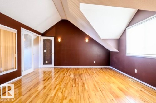 Hardwood flooring spanning a spacious room with a vaulted ceiling, brown walls, and multiple windows - 18633 122 Avenue, Edmonton, AB - Indoor Photo Showing Other Room