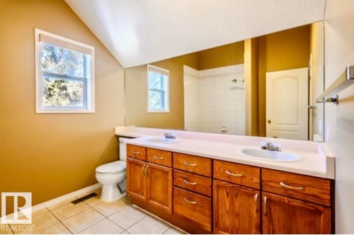 Bathroom featuring a double vanity with wood cabinetry, two undermount sinks, and a single window - 18633 122 Avenue, Edmonton, AB - Indoor Photo Showing Bathroom