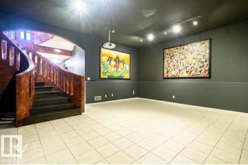 Lower level theatre room. Curved staircase with dark wood-finish treads and an ornate banister - 18633 122 Avenue, Edmonton, AB - Indoor Photo Showing Other Room