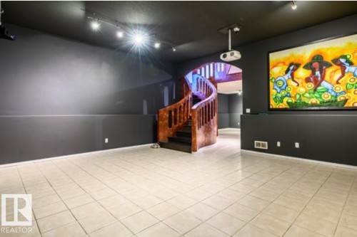 Spacious room featuring light-toned tile flooring, dark gray walls, and a recessed black ceiling with track lighting - 18633 122 Avenue, Edmonton, AB - Indoor Photo Showing Other Room