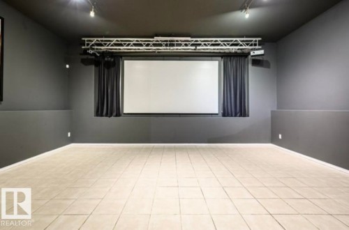 Dedicated media room featuring a large projection screen and dark privacy curtains - 18633 122 Avenue, Edmonton, AB - Indoor
