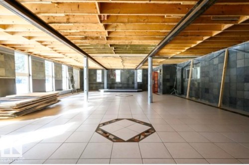 Open-plan interior featuring a tiled floor with an octagonal inlay, exposed wood ceiling joists, and a perimeter of windows - 18633 122 Avenue, Edmonton, AB - Indoor Photo Showing Other Room