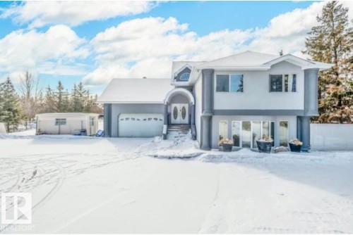 Two-story stucco exterior featuring prominent fluted columns and a double-wide garage with a curved archway entrance - 18633 122 Avenue, Edmonton, AB - Outdoor With Facade