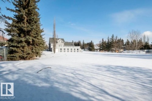 Expansive snow-covered grounds with a detached property featuring a pitched roofline, multiple windows, and a surrounding natural treeline - 18633 122 Avenue, Edmonton, AB - Outdoor With View