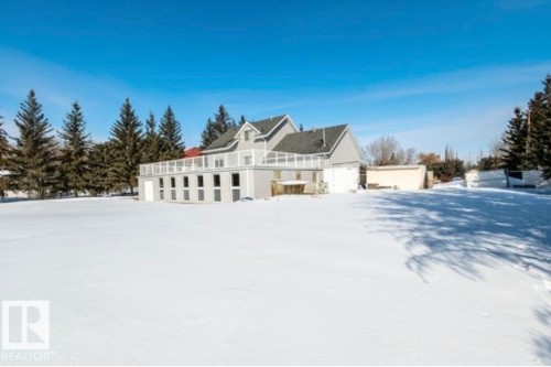 Contemporary residence featuring a spacious elevated deck with white railing, multiple lower-level windows, and a prominent gable roofline - 18633 122 Avenue, Edmonton, AB - Outdoor