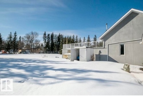 Rear exterior featuring a large upper deck with white railing, a ground-level entrance, and a window with white trim - 18633 122 Avenue, Edmonton, AB - Outdoor