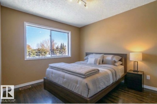 Virtually staged. Room featuring a large white-trimmed window, wood-finish flooring, neutral wall tones, and recessed ceiling lighting - 18633 122 Avenue, Edmonton, AB - Indoor Photo Showing Bedroom