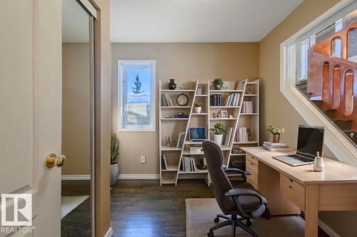 Virtually staged. Dedicated workspace featuring wood-finish flooring and a built-in shelving unit - 18633 122 Avenue, Edmonton, AB - Indoor Photo Showing Office