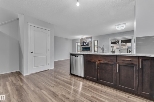 Kitchen island featuring dark wood cabinetry, stainless steel dishwasher, and a light-toned countertop - 718 177 Street, Edmonton, AB - Indoor Photo Showing Kitchen