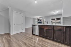 Kitchen island featuring dark wood cabinetry, stainless steel dishwasher, and a light-toned countertop - 