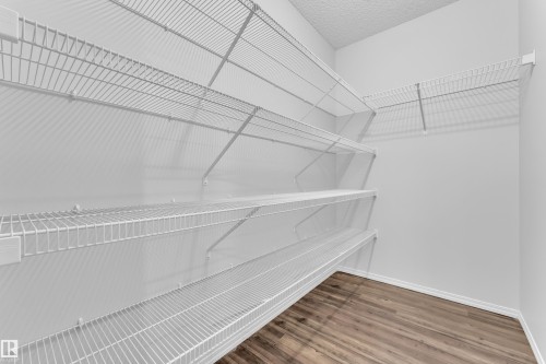 Closet featuring extensive wire shelving, white wall finishes, and wood-finish flooring - 718 177 Street, Edmonton, AB - Indoor With Storage