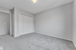 Interior room featuring light gray walls, gray patterned carpeting, and white baseboards - 