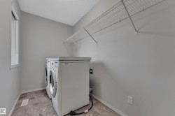 Dedicated laundry area featuring a window, light gray walls, a built-in wire shelf, and stone-finish flooring - 