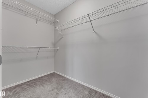 Spacious closet featuring white wire shelving, light gray wall paint, white baseboards, and gray patterned carpeting - 718 177 Street, Edmonton, AB - Indoor With Storage