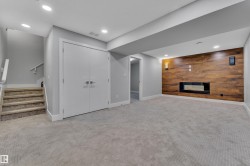 Spacious lower-level area featuring a modern linear fireplace set into a wood-finish accent wall - 
