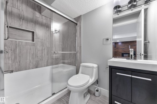Bathroom featuring a full tub with glass sliding doors, a built-in shower niche, and floor-to-ceiling tile surround - 718 177 Street, Edmonton, AB - Indoor Photo Showing Bathroom