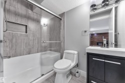 Bathroom featuring a full tub with glass sliding doors, a built-in shower niche, and floor-to-ceiling tile surround - 