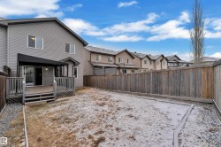 Expansive backyard featuring a privacy fence, wood-finish deck with railing, sliding glass door access, exterior lighting, and a partial awning - 