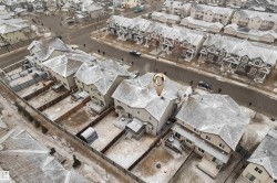 Aerial view of a residential neighborhood featuring detached homes with pitched roofs and private fenced backyards - 