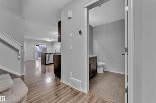 Open concept living area with wood-finish flooring, a kitchen island, and stainless steel appliances - 718 177 Street, Edmonton, AB - Indoor Photo Showing Other Room