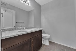 Bathroom vanity featuring a light-toned countertop, an undermount sink with a chrome faucet, and dark wood cabinetry with gold-tone hardware - 