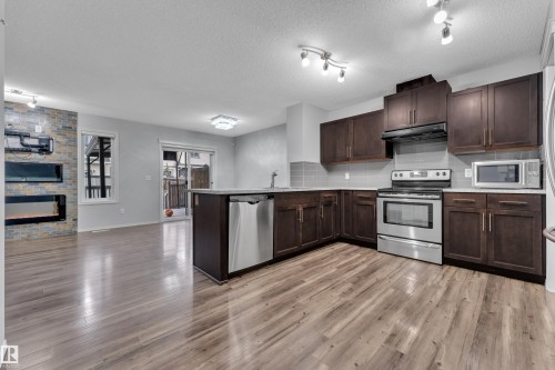 Modern kitchen featuring dark wood cabinetry, stainless steel appliances, and wood-finish flooring - 718 177 Street, Edmonton, AB - Indoor Photo Showing Kitchen