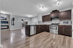Modern kitchen featuring dark wood cabinetry, stainless steel appliances, and wood-finish flooring - 